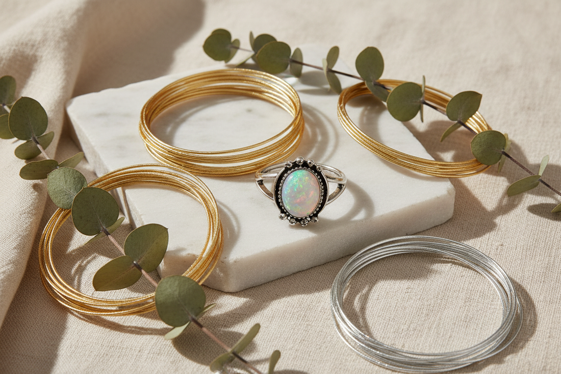 Gold wire bangles, silver wire bangles, and a moonstone glass stone ring arranged on linen with eucalyptus — handmade jewellery by Arnia CraftyGirl