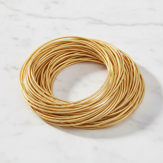 Gold memory wire spring bangles stacked on white marble surface - Arnia CraftyGirl